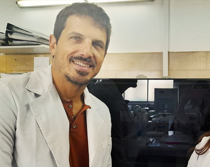 Augusto Crespi durante una expedición científica en la costa patagónica, observando muestras marinas con indumentaria de campo.
